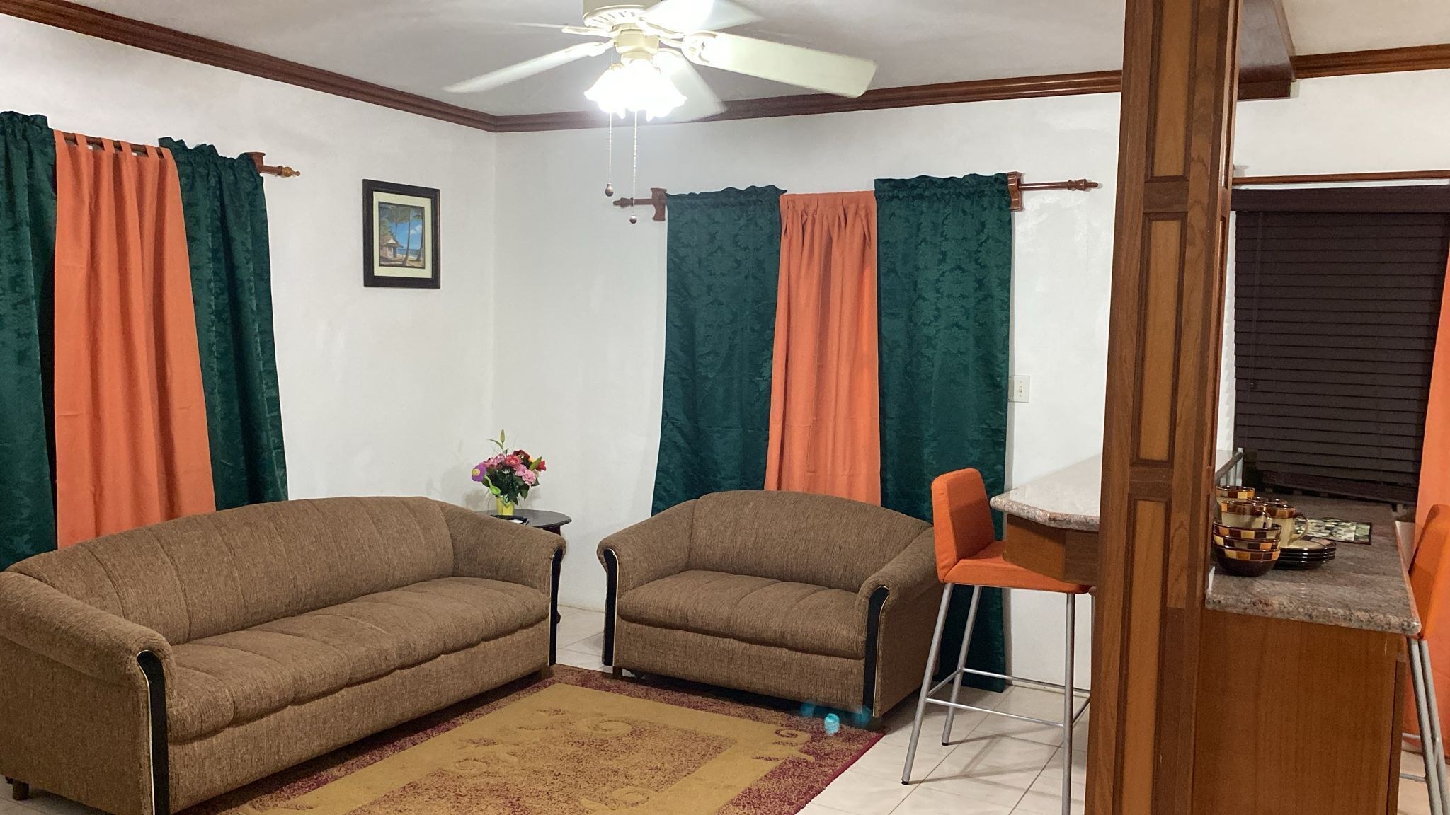 Ein Wohnzimmer mit zwei Sofas, einem kleinen Tisch mit Blumenvase und einem Deckenventilator.