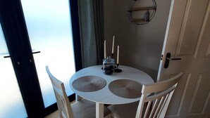 A small dining area with a round table, two chairs, a candle holder, and a view through a door. - The Annex @ Holly Glenn a cosy couple's retreat (Clint Green)