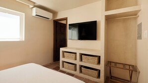 Quarto com cama, televisão fixada na parede, guarda-roupa e cestos embutidos para arrumação.