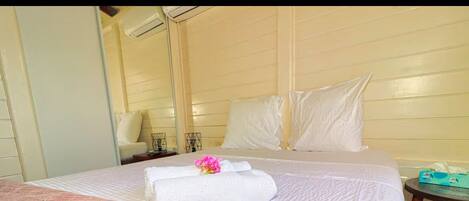 A bed with a white pillow and a folded white towel.