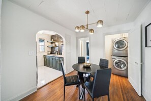 A dining area with a round table, black chairs, and a chandelier.