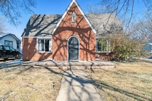 A single-story brick house with a gabled roof, a front door, and a small porch.