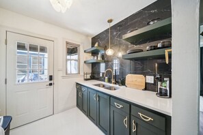 A modern kitchen with dark cabinets, a white countertop, a built-in stove, and a coffee maker.