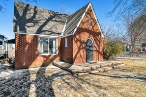 A brick building with a gabled roof, a front door, and a small porch.