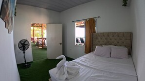 A bedroom with a bed, a fan, and a view of an outdoor area.