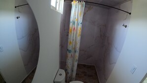A small, compact bathroom with a toilet, bidet, and shower curtain.