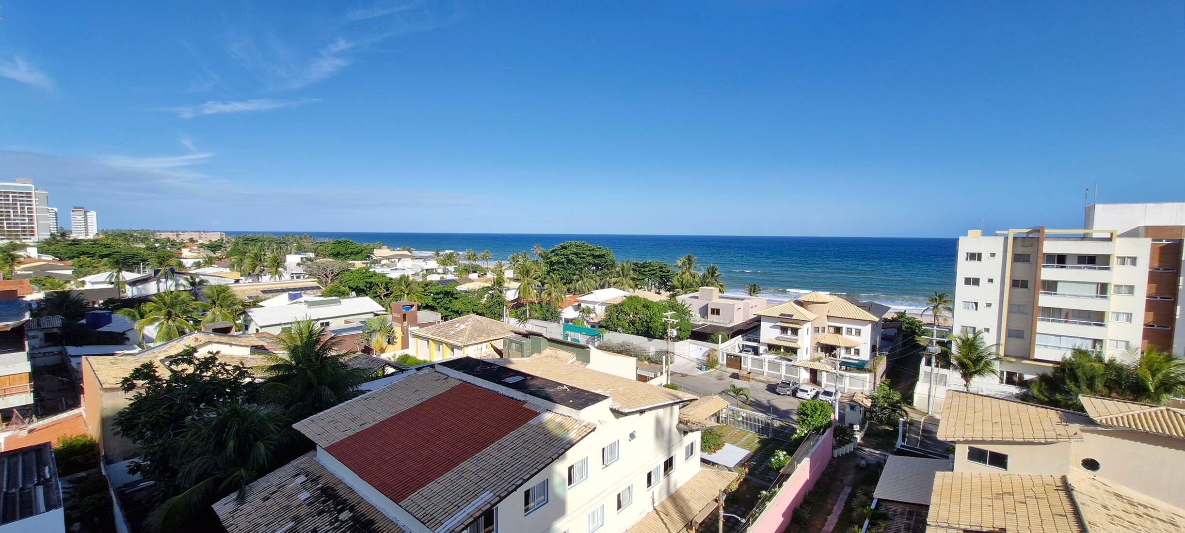 Una zona residenziale costiera con edifici, alcuni con balconi, e una vista libera sul mare.