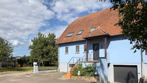 Ein zweigeschossiges Haus mit rotem Ziegeldach, Garage und einer kleinen Veranda.