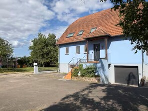 Ein zweigeschossiges Haus mit rotem Ziegeldach, Garage und einer kleinen Veranda.