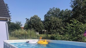 Ein oberirdischer Swimmingpool mit einer weißen, aufblasbaren Abdeckung, umgeben von einer Rasenfläche und Bäumen.