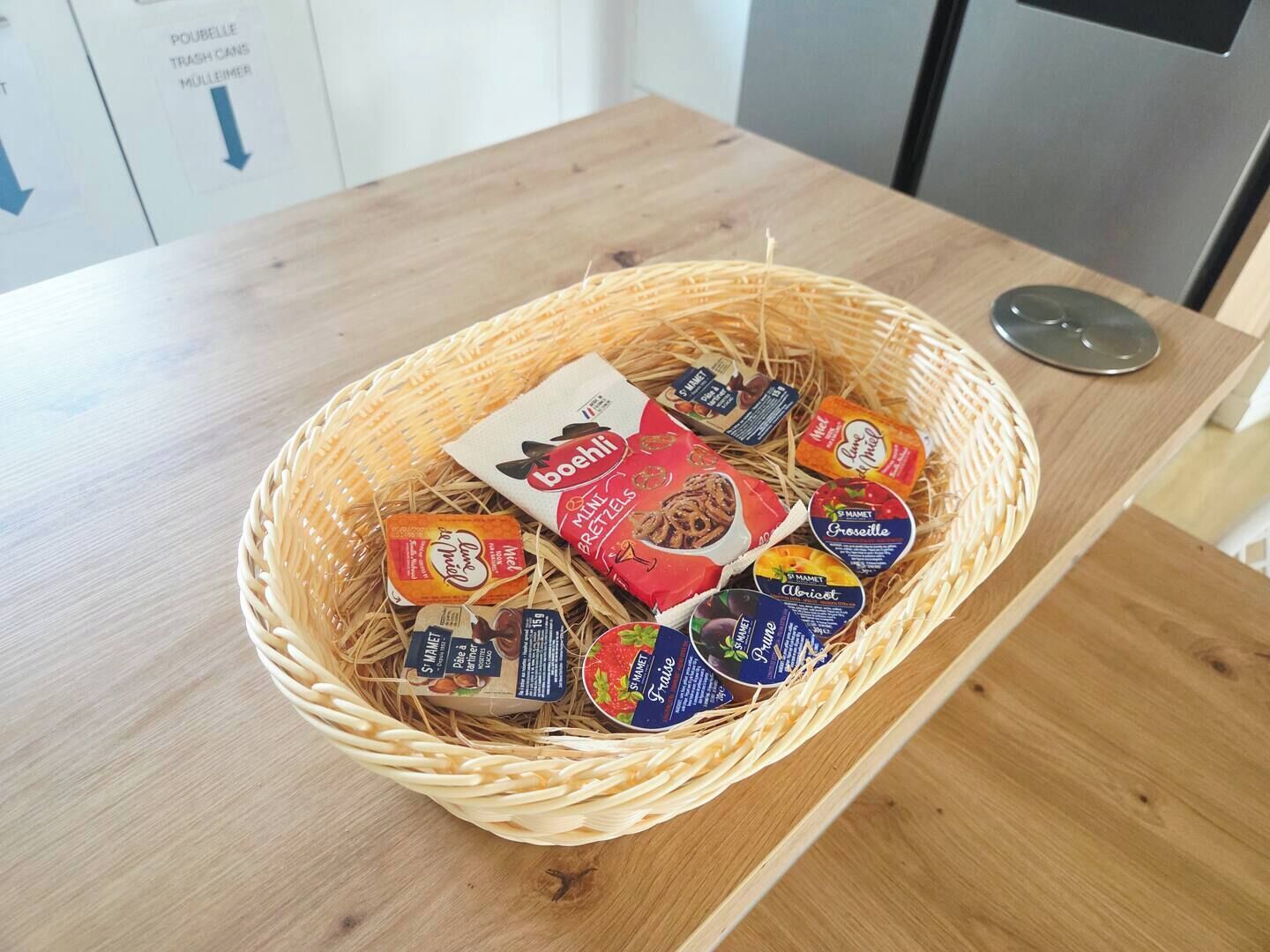 A wicker basket filled with various food items on a wooden table.