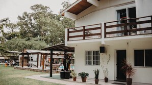 A two-story building with a balcony, potted plants, and a covered outdoor seating area. - Pousada Recanto das Cerejeiras (Rio Grande)