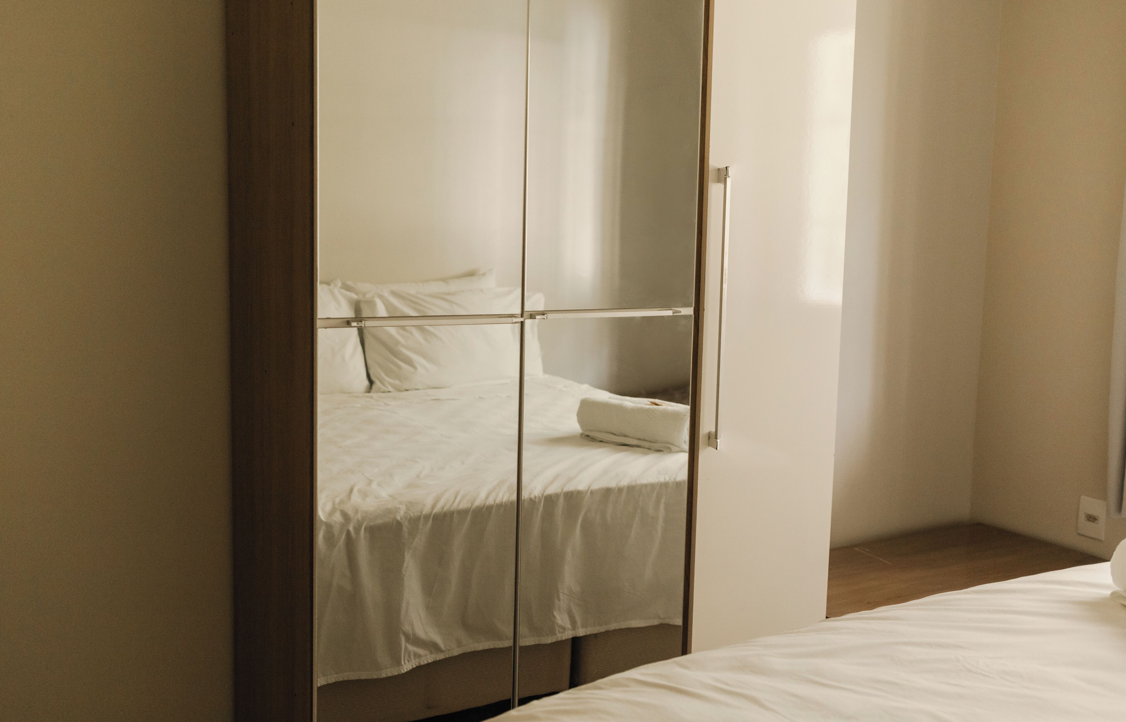 A bedroom with a bed, a wardrobe, and a mirror.