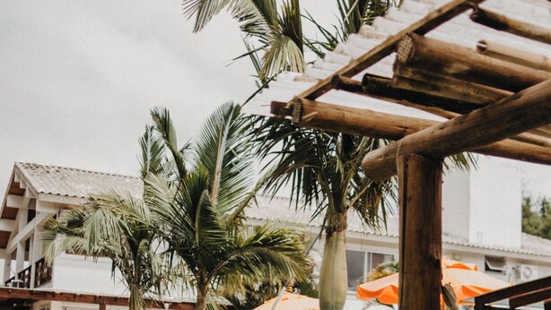 A pool area with palm trees, a hammock, and outdoor seating. - Pousada Recanto das Cerejeiras (Rio Grande)