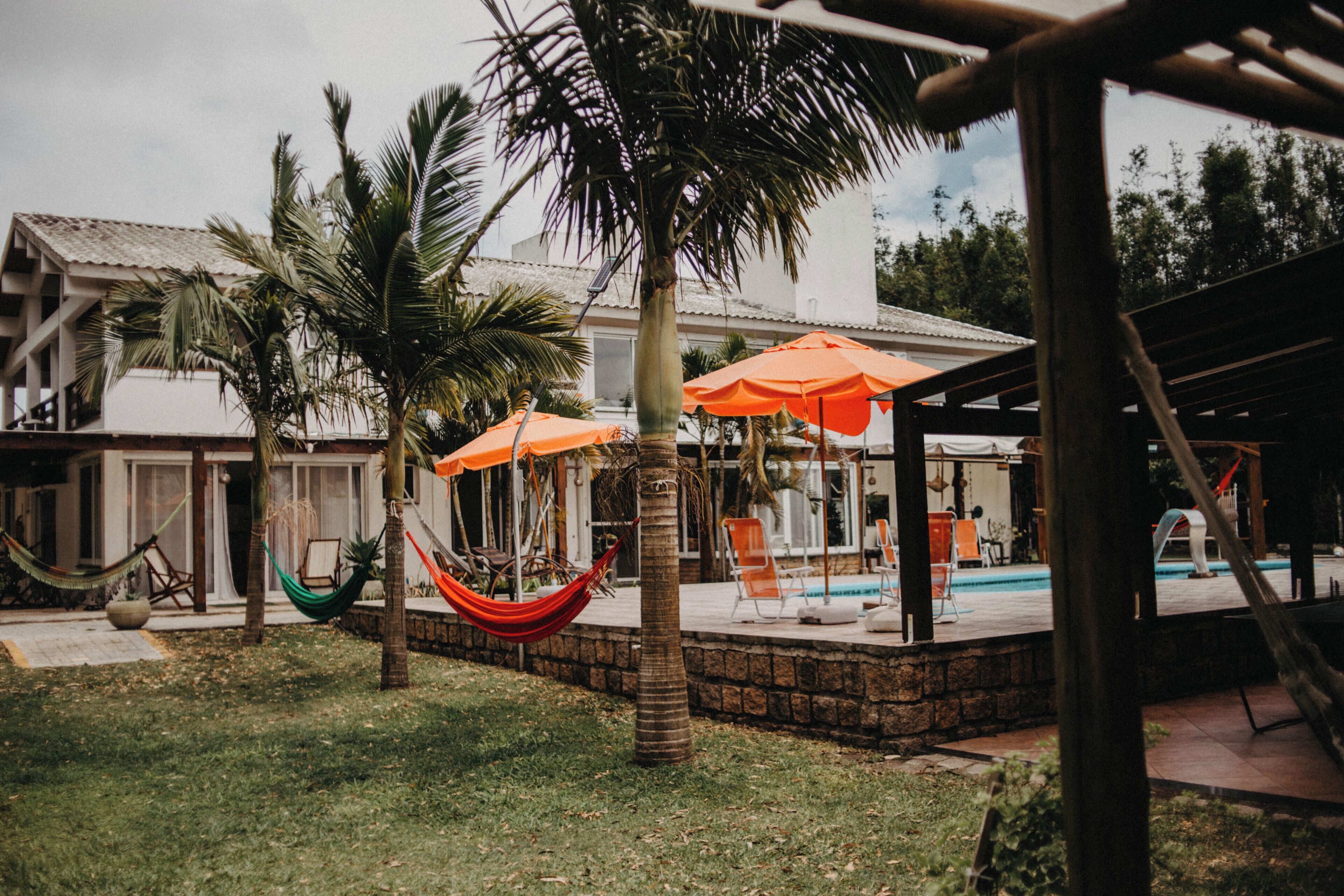 A pool area with a hammock, chairs, and umbrellas.
