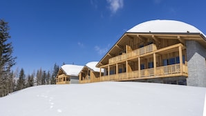 A wooden lodge with a snow-covered roof, wooden balconies, and a clear blue sky. - Apartment in La Rosiere With Panoramic Views (Montvalezan)