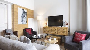 A modern living room with a sofa, armchairs, a television, and a wooden cabinet. - Apartment in La Rosiere With Panoramic Views (Montvalezan)