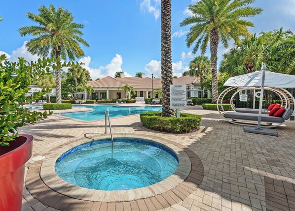 A pool area with a hot tub, lounge chairs, and a sign with spa rules.
