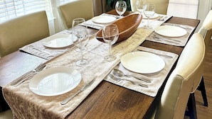 Un comedor con una mesa de madera dispuesta para cuatro personas, rodeada de sillas.