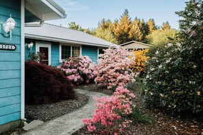 Ein Haus mit der Nummer 1721, umgeben von einem Garten mit rosa und gelben Blumen.