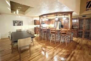 Un comedor amplio con una mesa y sillas de madera oscura, un muro de acento de piedra y armarios de madera al fondo.