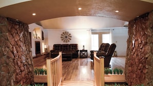 Un salón amplio con un sofá, un sillón y un elemento decorativo en la pared.