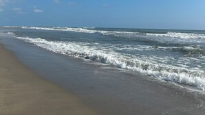 A beach with waves approaching the shore under a clear sky.