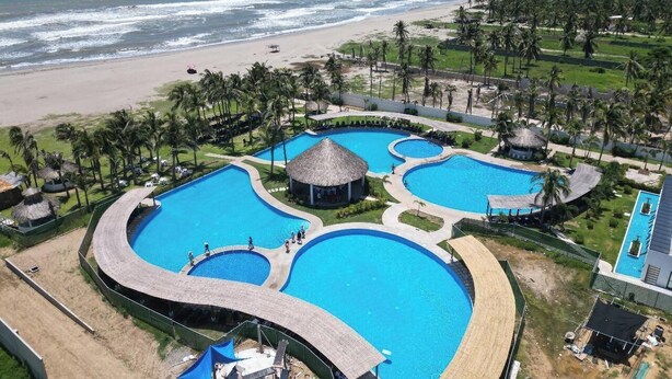 A resort with multiple swimming pools, a beach, and palm trees.