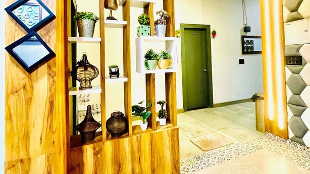 Un intérieur moderne avec un séparateur en bois, des étagères ornées d’objets décoratifs et un sol à motifs.