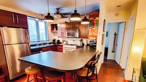 A modern kitchen with a large island, stainless steel appliances, and pendant lighting.