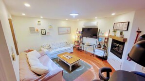 A cozy living room with a sofa, a coffee table, a TV, and a fireplace.