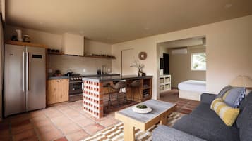 Una cocina moderna con una isla central, taburetes de bar y un área de comedor con sofá y una mesa de centro.