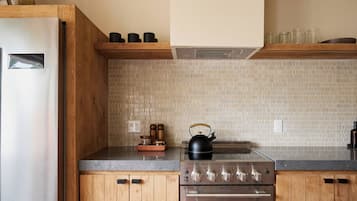 Una cocina con armarios de madera, un refrigerador de acero inoxidable, un hervidor y una estufa.
