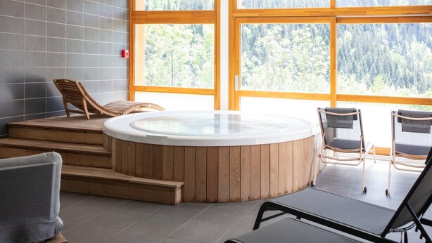 Zona de spa con bañera de hidromasaje, escalones de madera y asientos.