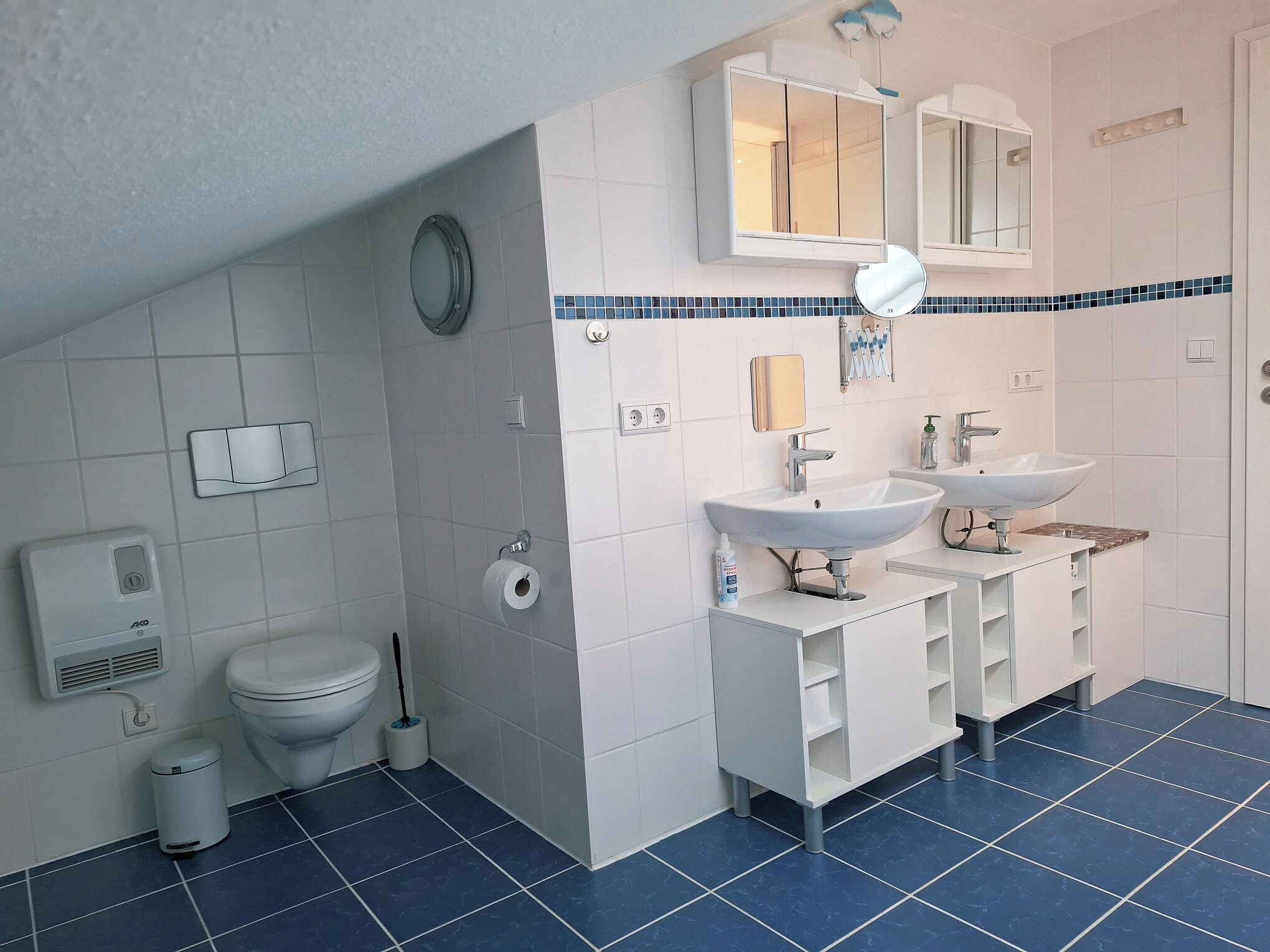 Une salle de bain moderne équipée de toilettes, d’un bidet, de deux lavabos et d’un miroir.