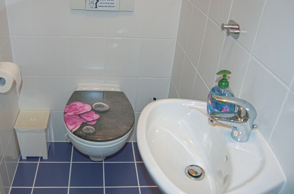 A bathroom with a toilet, sink, and a toilet paper holder.