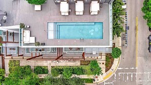 Zona de piscina en la azotea con sillones y una piscina.