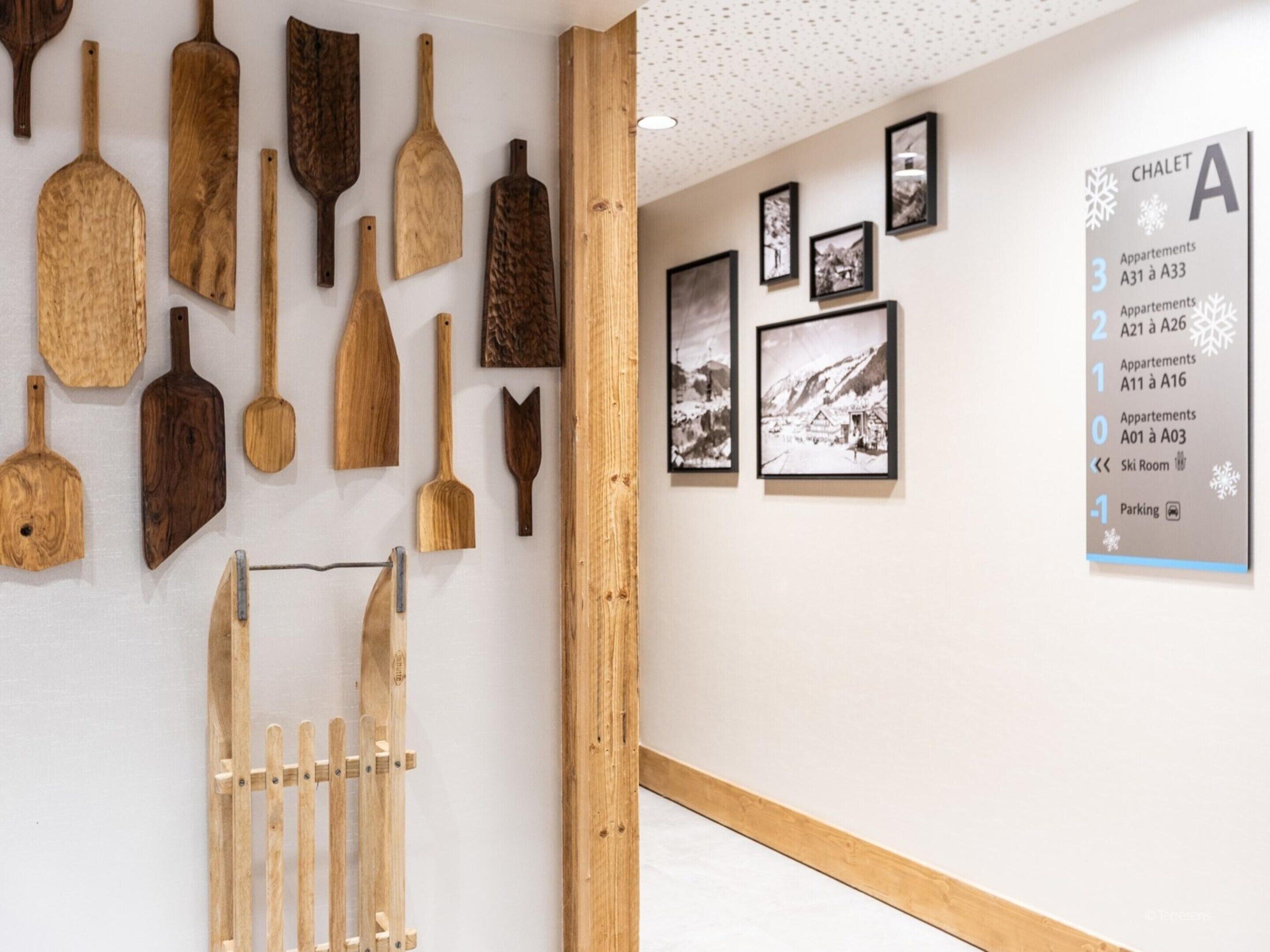 A hallway with wooden wall-mounted tools and a sign indicating room numbers and amenities.