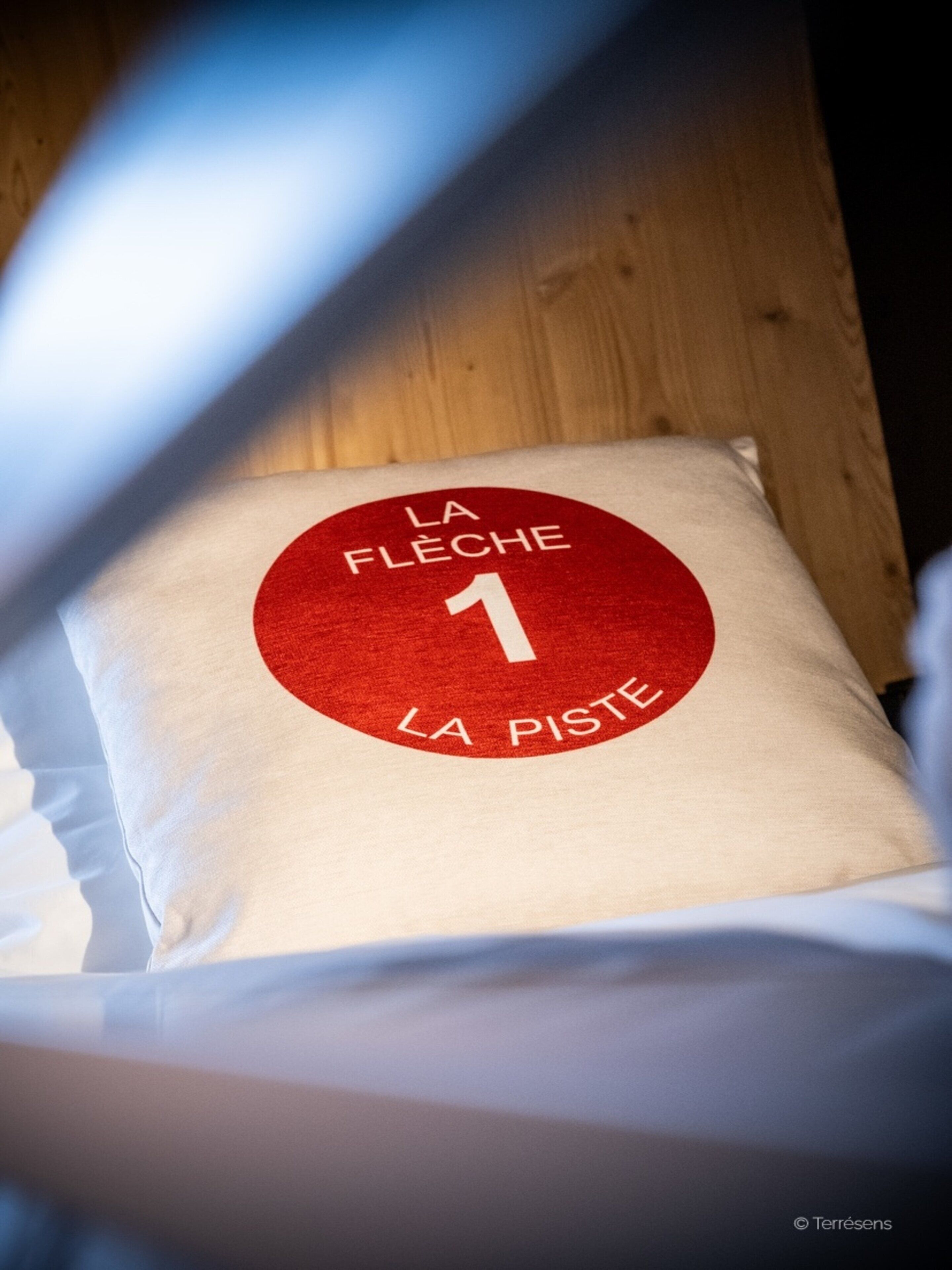 A pillow with a logo and text indicating it is from 'La Flèche 1 La Piste'.