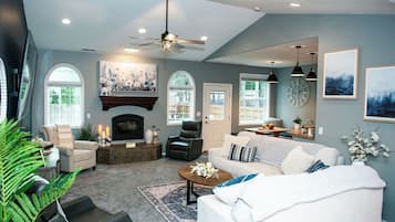 A spacious living room with a fireplace, comfortable seating, and large windows.