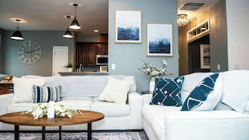 A living room with a white sofa, a coffee table, and a clock on the wall.