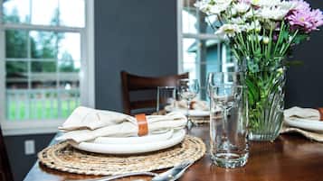 Una mesa de comedor con un mantel tejido, un florero de vidrio transparente y una servilleta doblada con una banda de cuero.