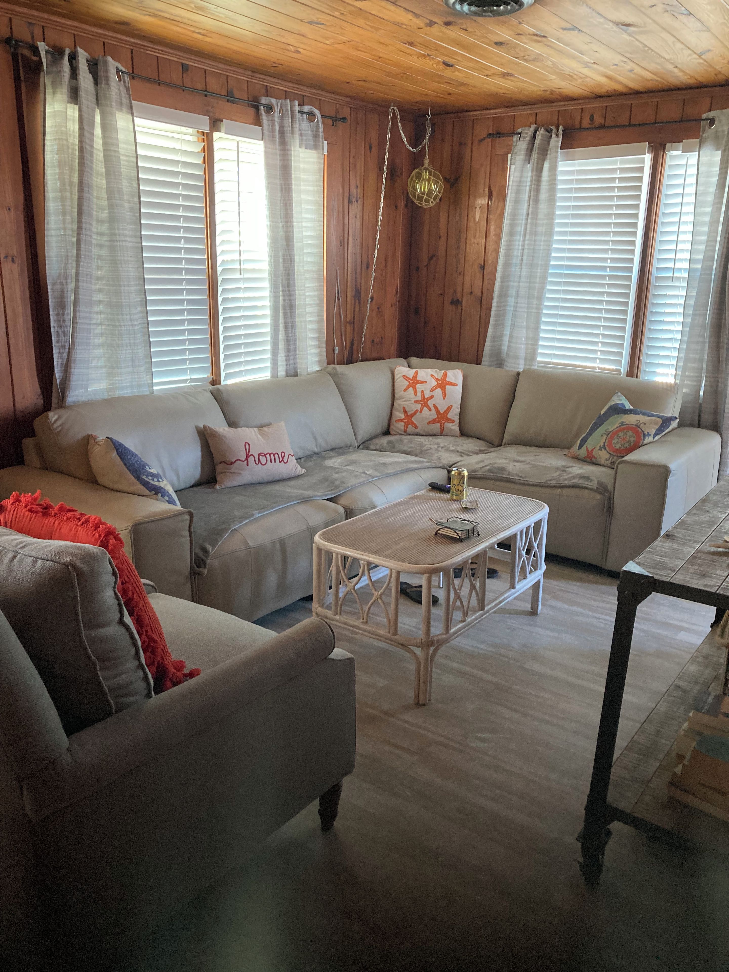 A cozy living room with a sectional sofa, a small coffee table, and a wooden ceiling.