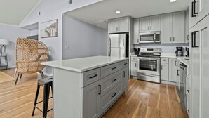 A modern kitchen with grey cabinets, a stainless steel refrigerator, a built-in oven, and a microwave.
