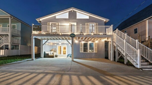 A two-story house with a balcony, a covered porch, and a staircase leading to the upper level.