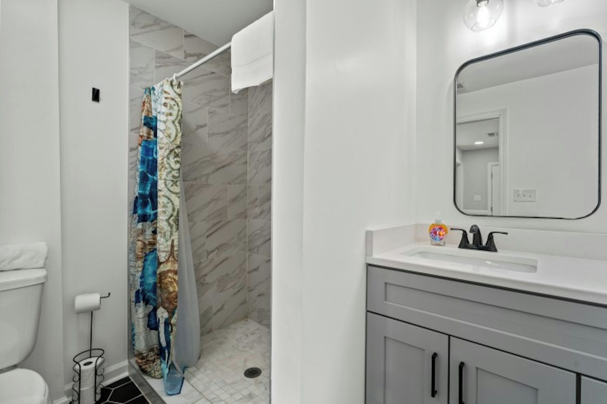 Une salle de bain équipée d’une douche, de toilettes, d’un lavabo et d’un miroir.