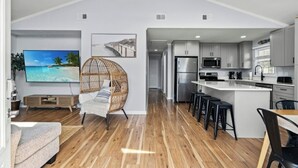 A modern kitchen with a large island, stainless steel appliances, and a dining area with bar stools.