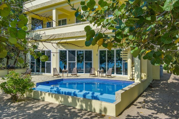 A two-story building with a swimming pool, outdoor seating, and large windows.