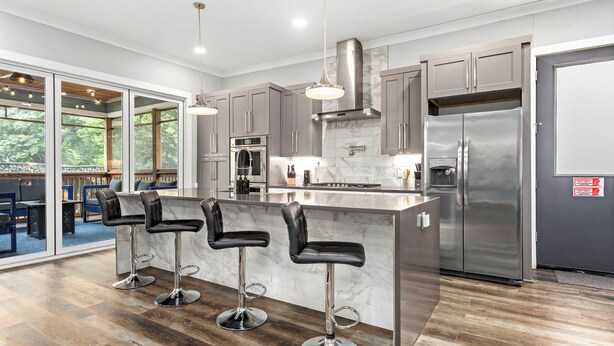 A modern kitchen with a large island, stainless steel appliances, and a view to the outside.