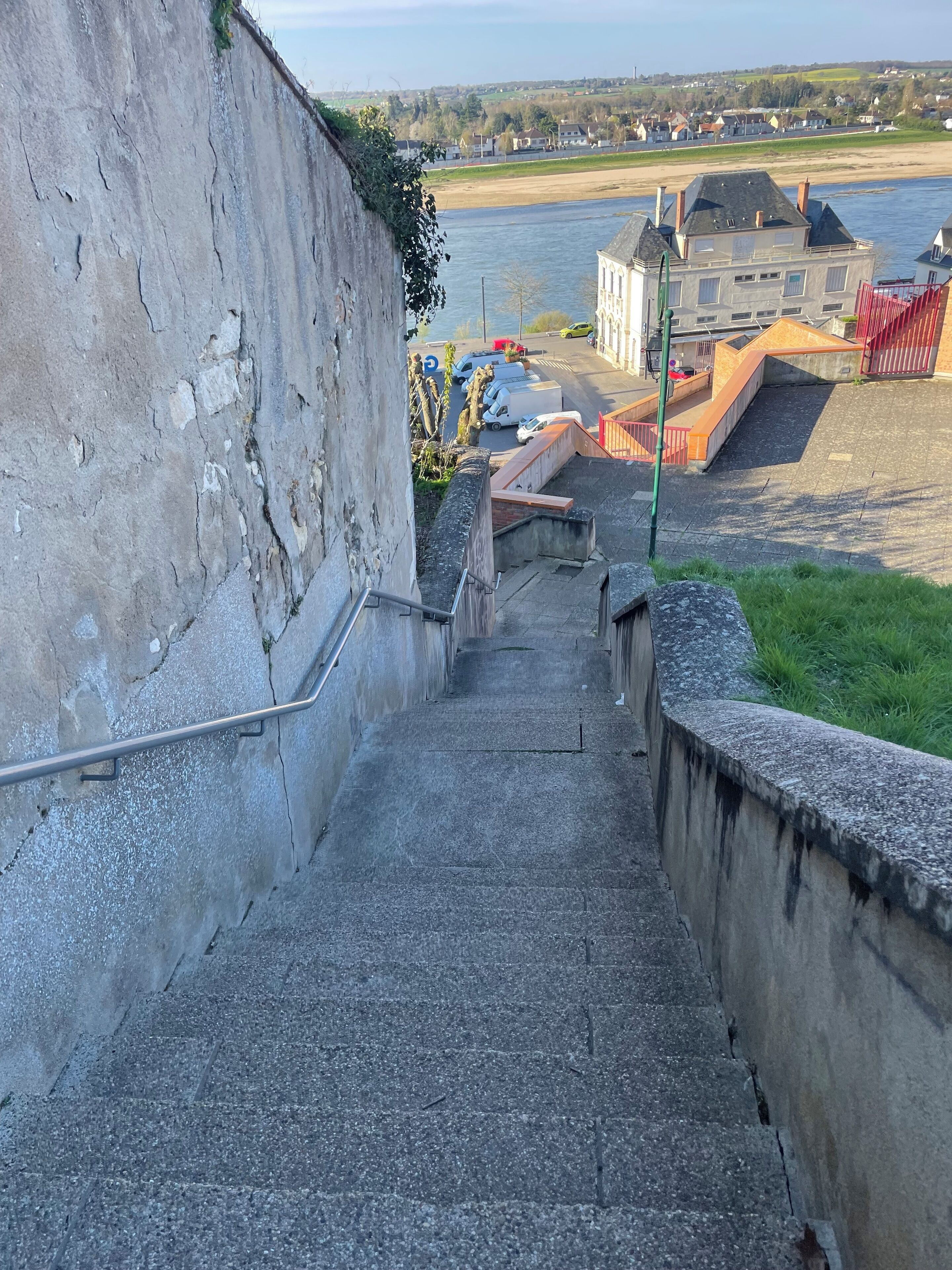 A set of stone steps leading down to a waterfront area with a view of a river and buildings in the background.